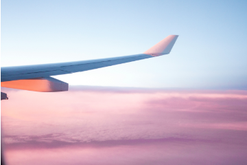 Airplane wing above pink clouds