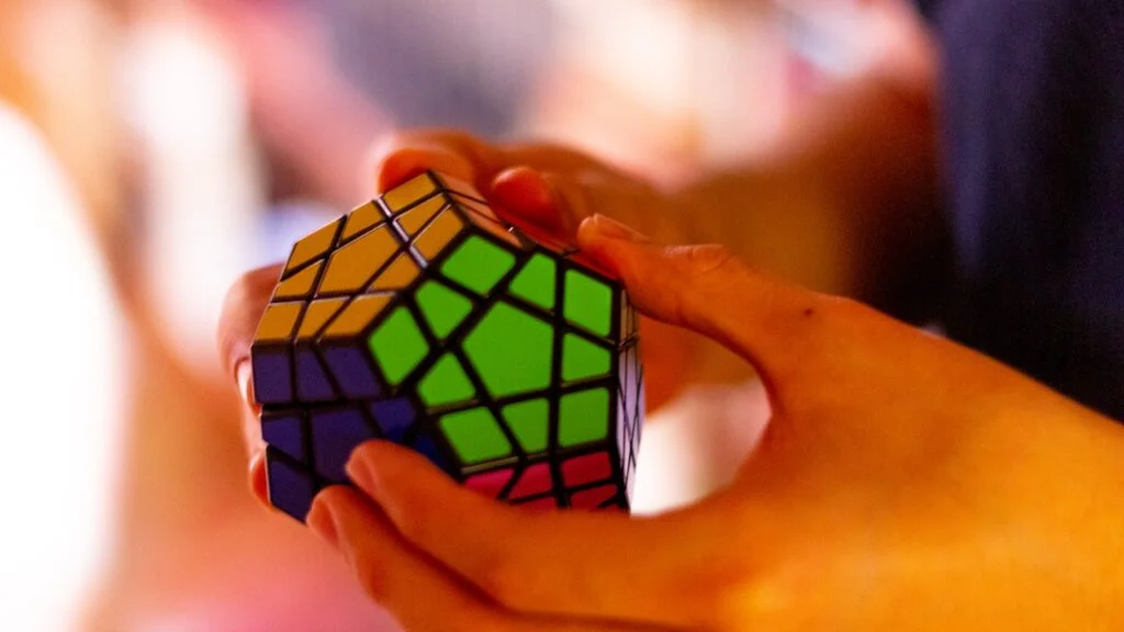 Hands solving a Rubik’s-style puzzle cube